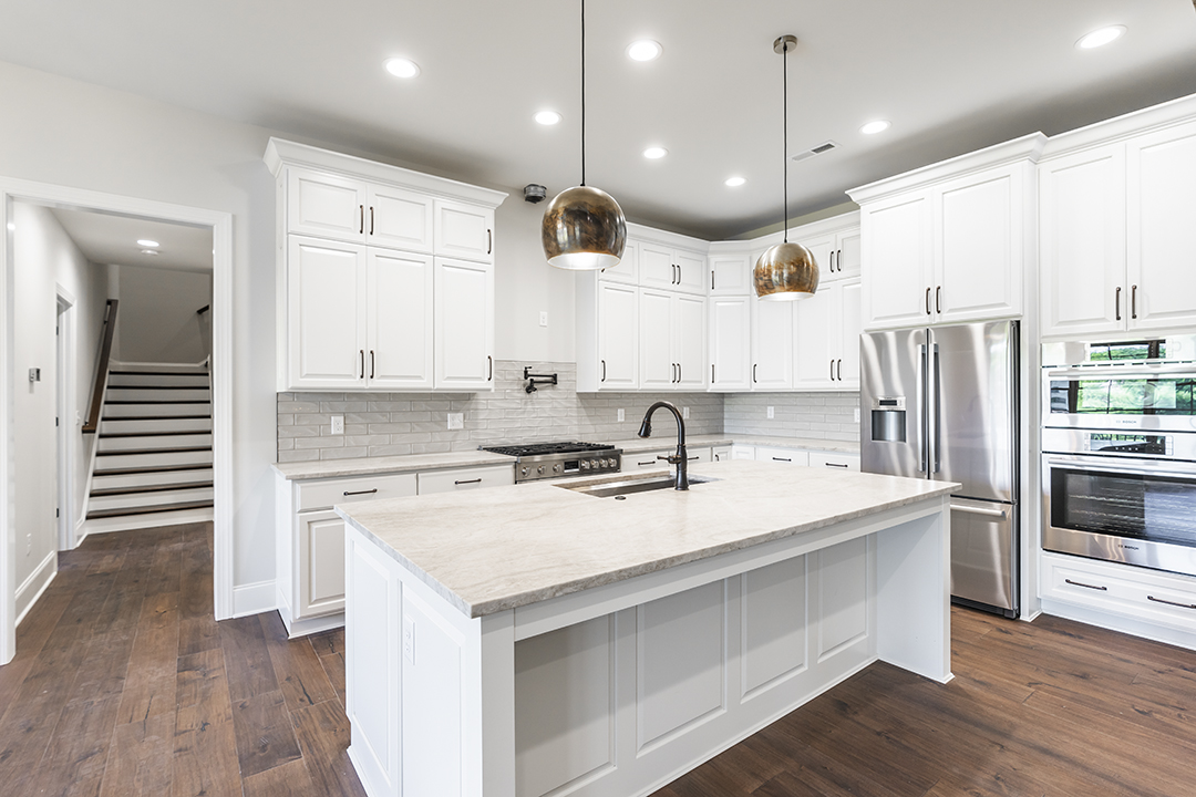 Custom home kitchen with white cabinetry and range hood